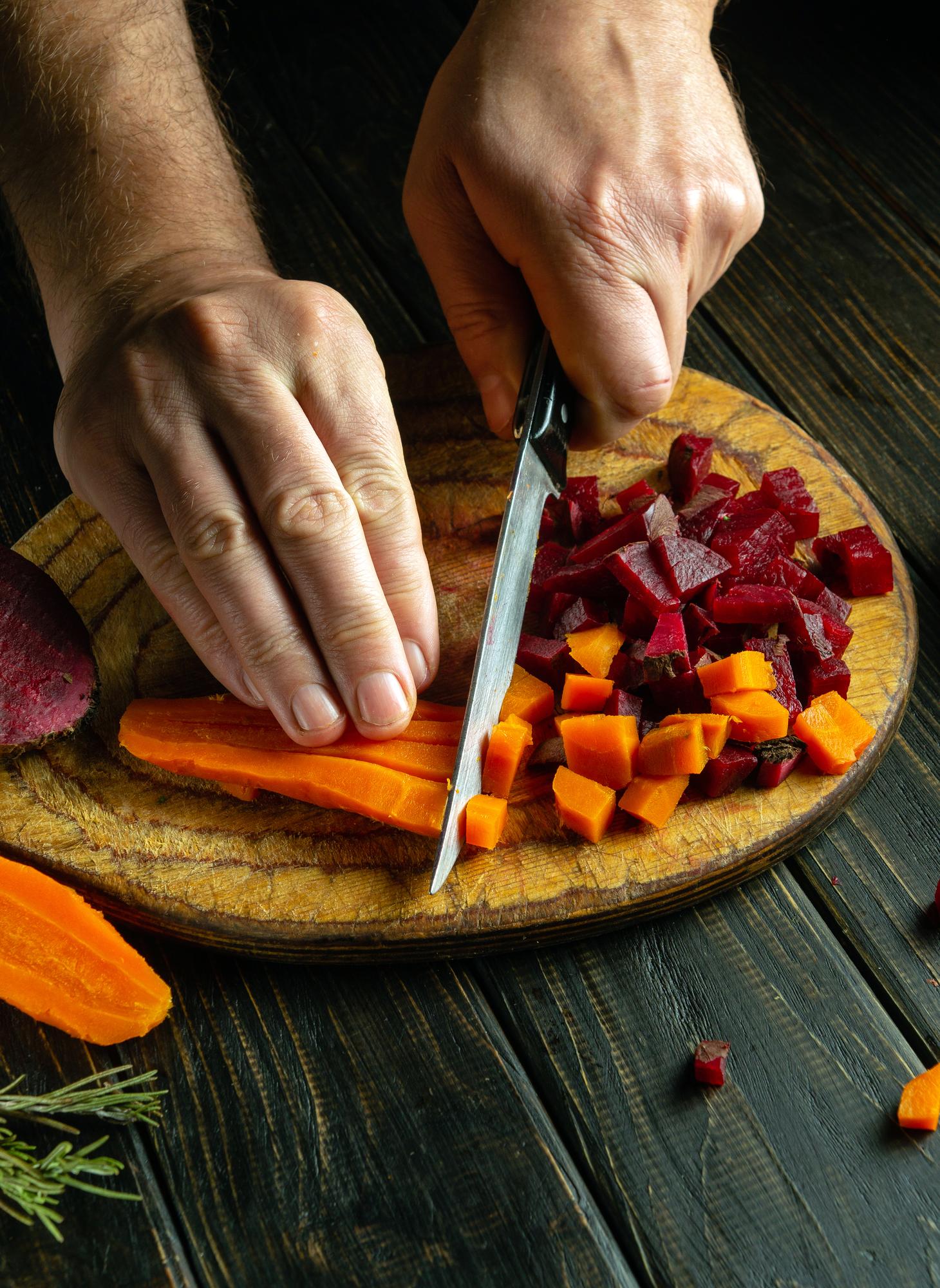Chef slicing roasted vegetables in rustic kitchen